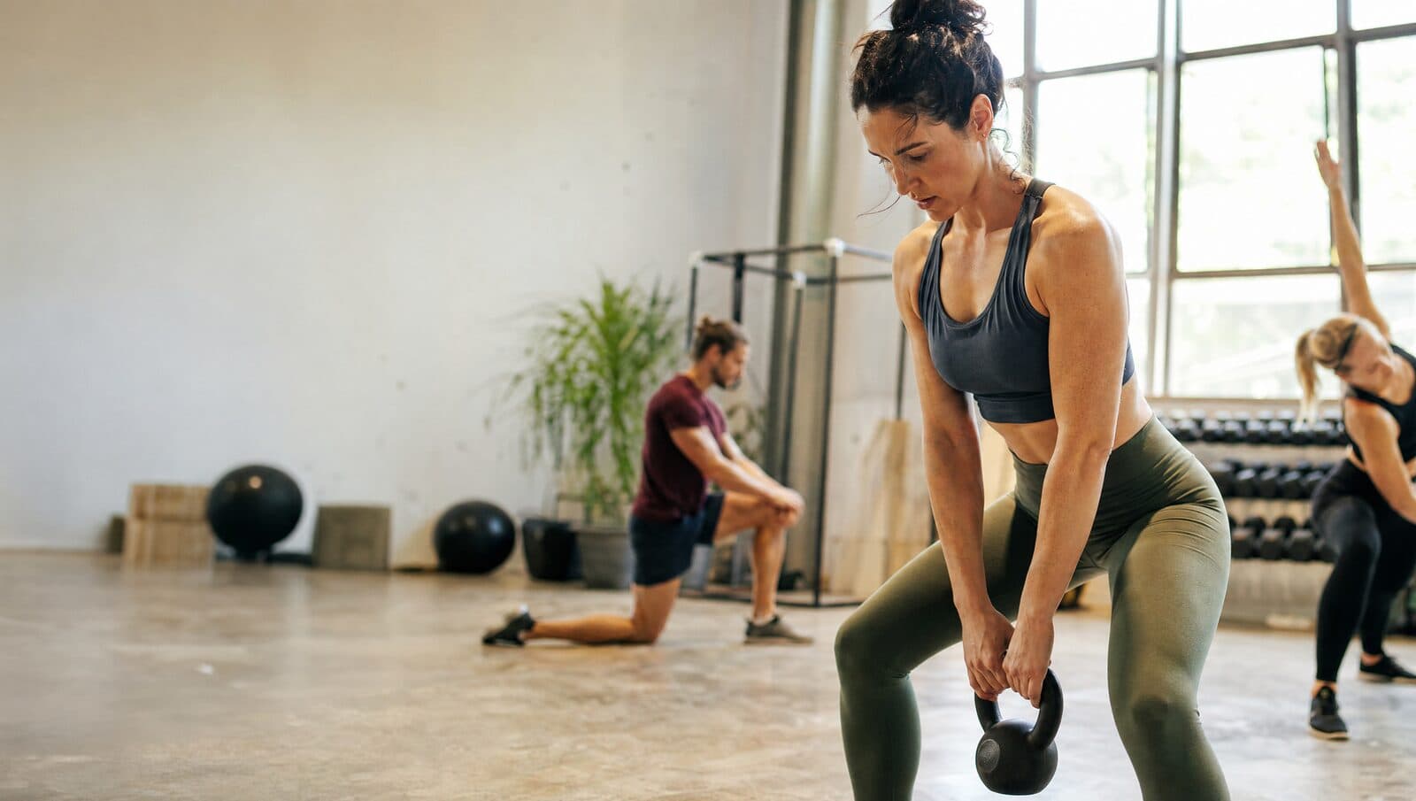 Socios entrenando con kettlebells en una sala luminosa del centro.